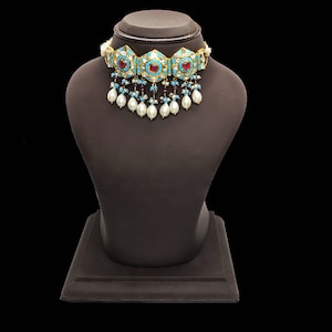 May include: A turquoise and gold choker necklace with red and white stones and pearl drops.