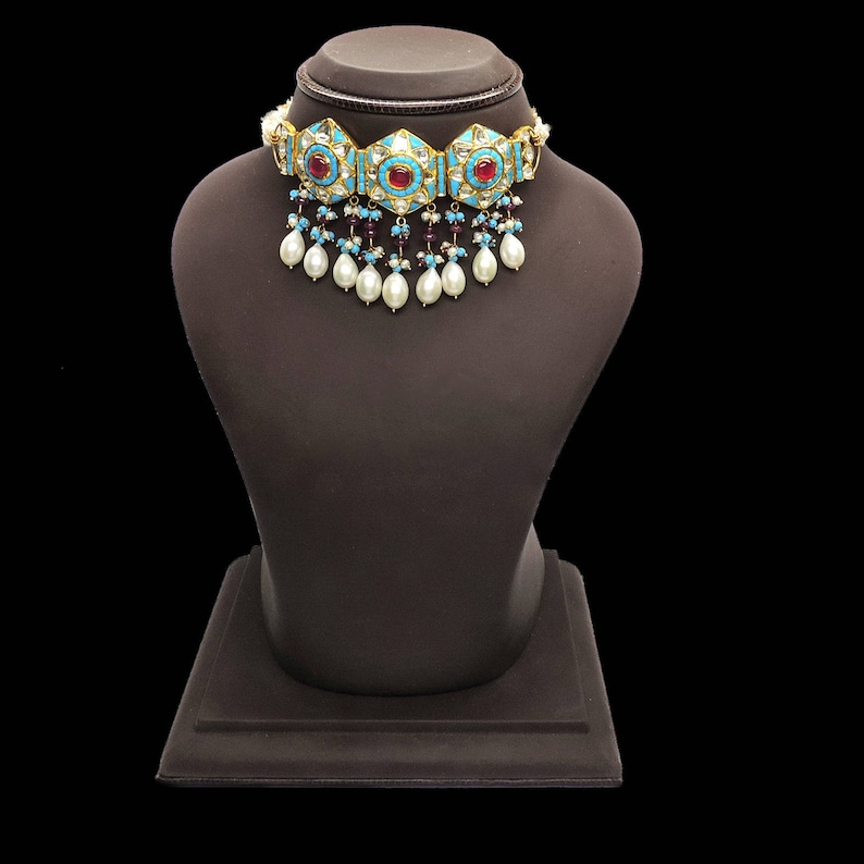 May include: A turquoise and gold choker necklace with red and white stones and pearl drops.