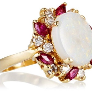 May include: A gold ring with a large white opal surrounded by smaller diamonds and red rubies.