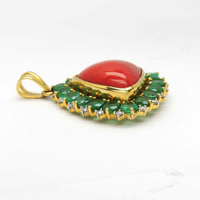 May include: A gold pendant featuring a heart-shaped red coral gemstone surrounded by a halo of emerald and diamond stones.