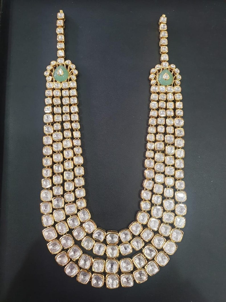 Pu&ograve; includere: Una collana d'oro con pi&ugrave; file di pietre chiare e accenti verdi. La collana &egrave; realizzata in oro e ha un design tradizionale.
