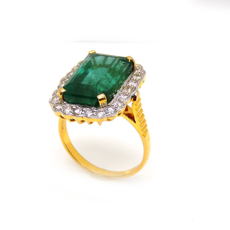 May include: A gold ring with a large emerald green gemstone surrounded by a halo of smaller diamonds.