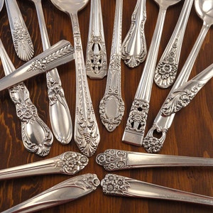 May include: A collection of vintage silver spoons with ornate designs. The spoons have a polished finish and intricate details.