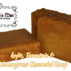 May include: Three bars of handmade soap with a golden-brown hue. The soap is labeled "kojic, Turmeric & Lemongrass Essential Soap" and "Gabriele's Mist Handmade Body Products". The bars have a rustic, textured appearance.