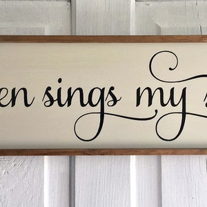 May include: A wooden sign with a cream background and a black cursive inscription that reads "Then sings my soul".