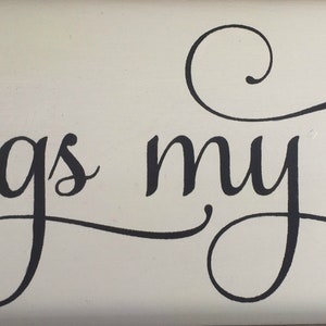 May include: A white wooden sign with black cursive lettering that reads "sings my soul".