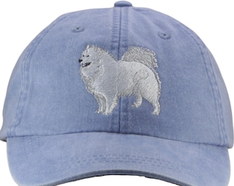 May include: A blue denim baseball cap with an embroidered white Pomeranian dog on the front.