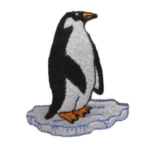May include: A black and white embroidered penguin standing on a blue and white embroidered ice floe.