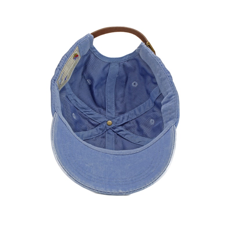 May include: A blue cotton baseball cap with a brown leather strap and a mesh lining. The cap is turned inside out, showing the interior.