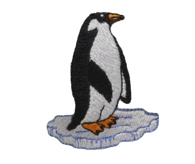 May include: A black and white embroidered penguin standing on a blue and white embroidered ice floe.