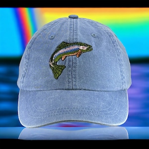 May include: A blue denim baseball cap with an embroidered trout design. The trout is green, brown, and orange.