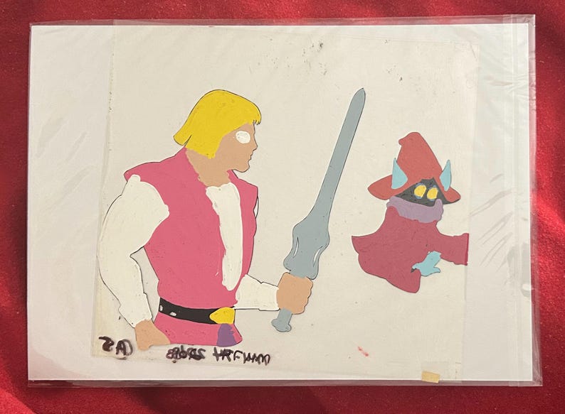 Puede incluir: Celda de animaci&oacute;n con dos personajes de dibujos animados. Un hombre rubio con ropa rosa y blanca sostiene una espada gris. A su lado, un personaje vestido de rojo con bufanda morada y sombrero con cuernos. La imagen tiene texto en la parte inferior.