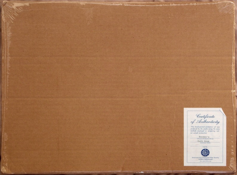 May include: A brown cardboard box with a white certificate of authenticity sticker. The sticker has the text "Certificate of Authenticity" and "This hand-signed animation of one produced by the studio using the same materials and techniques as the original production." It also includes the text "Roadster's "Back Seat" 2004" and a logo for the International Animated Film Society.