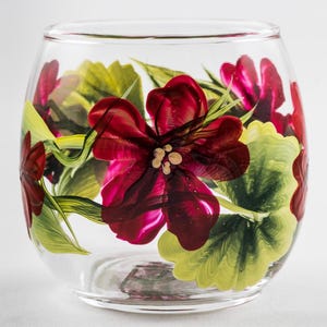 May include: A clear glass wine glass with a hand-painted design of red and green flowers. The flowers are painted in a realistic style and have a vibrant color.