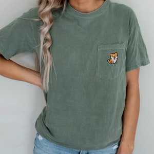 May include: A green t-shirt with a small embroidered Shiba Inu dog on the pocket.