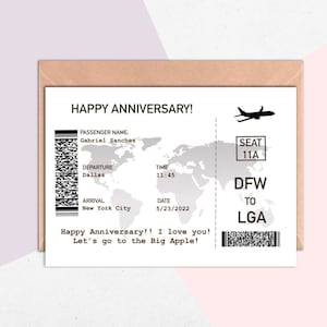May include: A white card with a black and white airplane ticket design. The card says "Happy Anniversary!" and "Let's go to the Big Apple!" The ticket is for a flight from Dallas to New York City on May 23, 2022. The passenger name is Gabriel Sanchez.