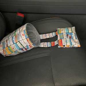 May include: A car trash bag and small pouch set. The bag and pouch are made of fabric printed with colorful license plates. The bag is cylindrical with a gray interior, and the pouch is rectangular. The set is designed to be used in a car.