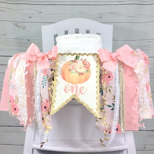May include: Pink and gold high chair banner with a pumpkin and floral design. The banner says "one" in gold script.