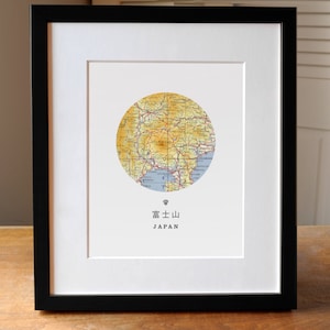 May include: A framed print of a map of Mount Fuji, Japan. The map is in a circle and is surrounded by a white border. The text "Mount Fuji, Japan" is printed below the map.