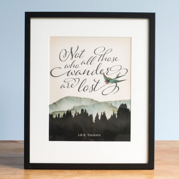May include: A framed wall art print featuring the text Not all those who wander are lost in black cursive script. The design includes a small colourful bird, a watercolour mountain range, and a dark forest silhouette with J.R.R. Tolkien at the bottom.