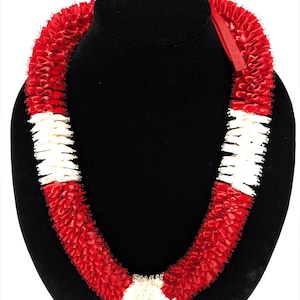 May include: A lei necklace constructed from folded red and white ribbon segments. The design features alternating sections of vibrant red and crisp white ribbon, creating a textured, ruffled appearance throughout the circular length of the accessory.