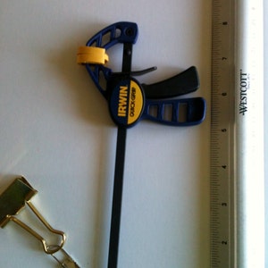 May include: A blue and yellow Irwin Quick-Grip clamp with a black handle and a metal bar. The clamp is 6 inches long and is next to a ruler.