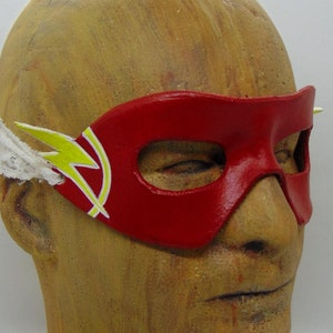 May include: A red leather mask with a yellow lightning bolt design. The mask is worn on a mannequin head.
