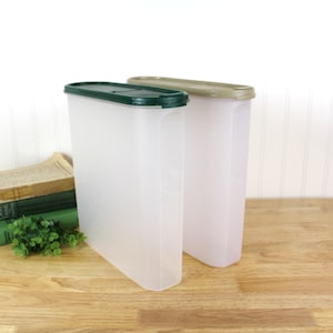 May include: Two clear plastic containers with lids. The container on the left has a green lid and the container on the right has a beige lid.