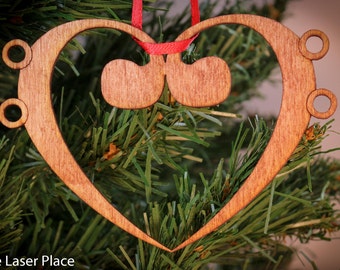 Op de afbeelding: Een houten hartvormige ornament met een treble clef-ontwerp. De ornament is bruin en heeft een rood lint eraan.
