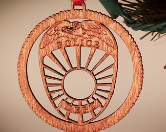 Könnte beinhalten: Ein hölzerner Weihnachtsbaumschmuck in Form eines Polizeibadgens mit einem Adlerdesign und der Aufschrift "POLICE".