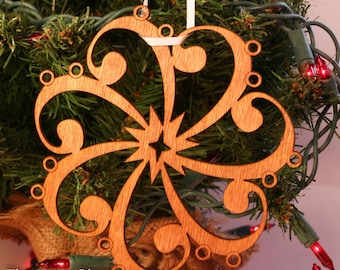 May include: A wooden Christmas ornament shaped like a star with intricate cutouts. The ornament is brown and has a white string attached to the top.