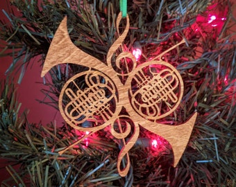 May include: A wooden Christmas ornament shaped like two French horns, with intricate details and a green ribbon.