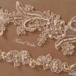 May include: Ivory lace trim with floral and leaf designs, embellished with pearls and sequins. The text "Tara Veils" is visible. This delicate trim is suitable for bridal wear and other special occasion projects.