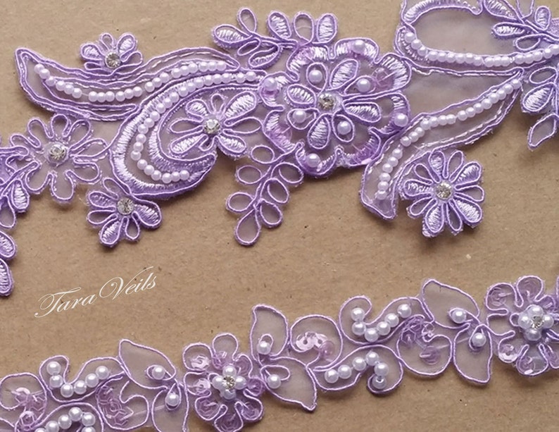 May include: Lilac floral lace trim with pearl and rhinestone embellishments. The trim is shown in two different designs, both with a delicate, feminine look.