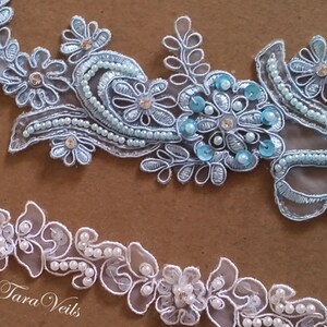 May include: Two pieces of delicate lace trim with pearl embellishments. The top trim is light blue with sequins and the bottom trim is white.