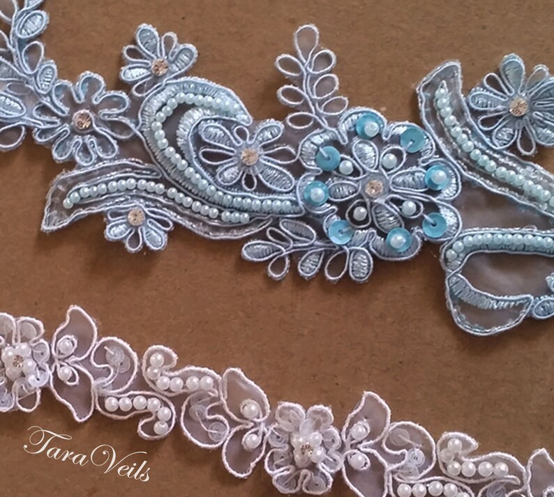 May include: Two pieces of delicate lace trim with pearl embellishments. The top trim is light blue with sequins and the bottom trim is white.