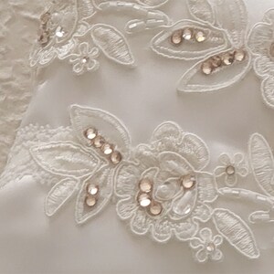 May include: White lace fabric with delicate floral patterns and small, clear rhinestones.