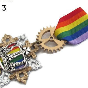 May include: A gold and silver crown with a rainbow flag design, attached to a gold gear and a rainbow ribbon with a purple backing. The text "FC13" is visible in the top left corner of the image.