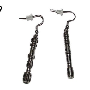 May include: A pair of silver earrings shaped like a sonic screwdriver, a fictional tool from the Doctor Who television series.