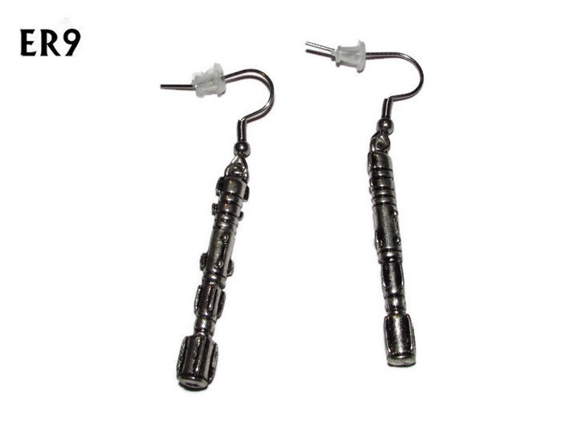 May include: A pair of silver earrings shaped like a sonic screwdriver, a fictional tool from the Doctor Who television series.