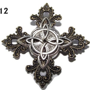 May include: A silver Celtic knot design in the center of a bronze cross with ornate details. The cross is a decorative piece with a vintage look.