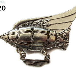 Könnte beinhalten: Eine silberfarbene Metallstifte in Form eines Luftschiffs mit Flügeln. Das Luftschiff hat ein detailliertes Design mit einem Gittermuster und einem Propeller am Heck. Die Flügel sind ausgebreitet und haben eine strukturierte Oberfläche. Der Stift ist mit "BV20" beschriftet.