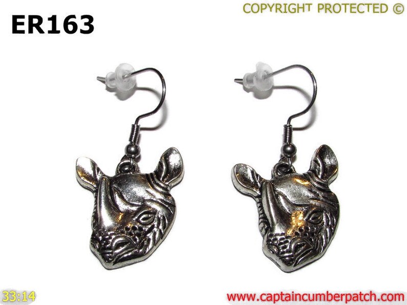 May include: Silver tone earrings featuring a detailed rhinoceros head design. The earrings have a hook closure.