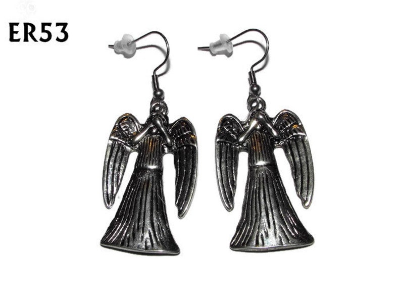 May include: A pair of silver angel earrings with a detailed design. The angels have wings and are in a praying position.