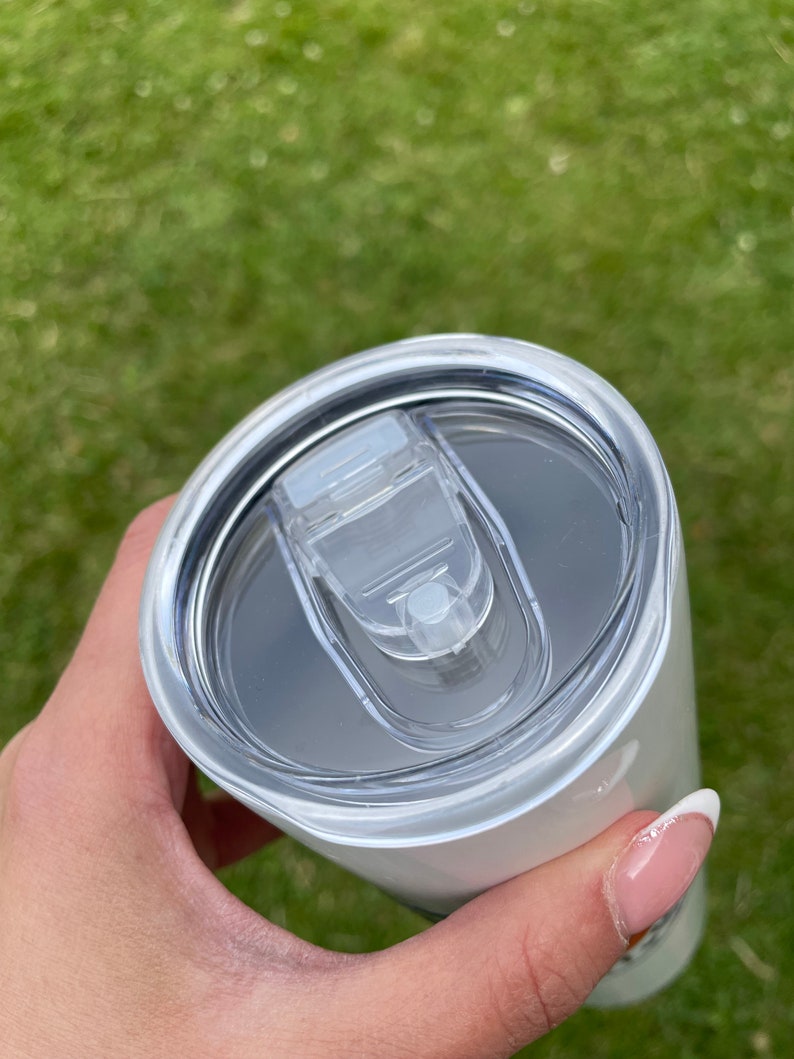 May include: White stainless steel tumbler with a clear lid. The lid has a small, clear handle.