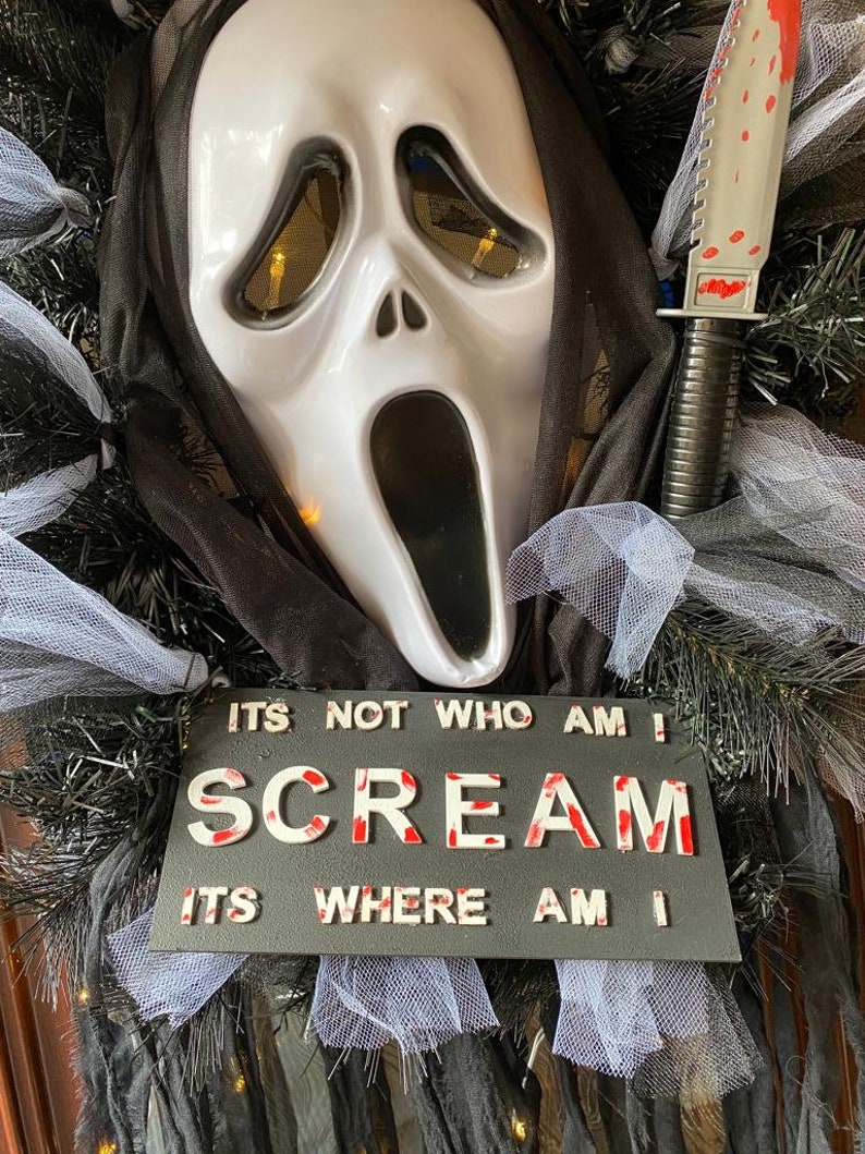 May include: A Halloween wreath with a white ghost mask, a black knife with red blood splatters, and a sign that reads "ITS NOT WHO AM I SCREAM ITS WHERE AM I".