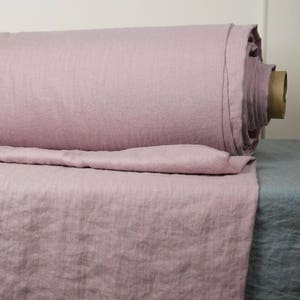 May include: A roll of soft, pale pink linen fabric. The fabric is unbleached and has a natural, slightly textured surface.