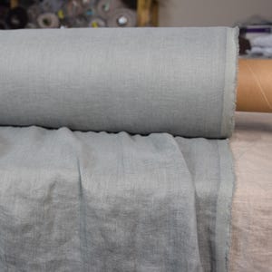 May include: A roll of light blue linen fabric. The fabric is soft and has a natural texture.