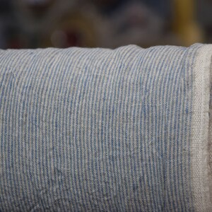 Puede incluir: Un rollo de tela rayada azul y blanca. La tela est&aacute; tejida con una textura de lino.