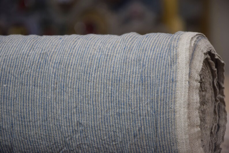 Puede incluir: Un rollo de tela rayada azul y blanca. La tela est&aacute; tejida con una textura de lino.